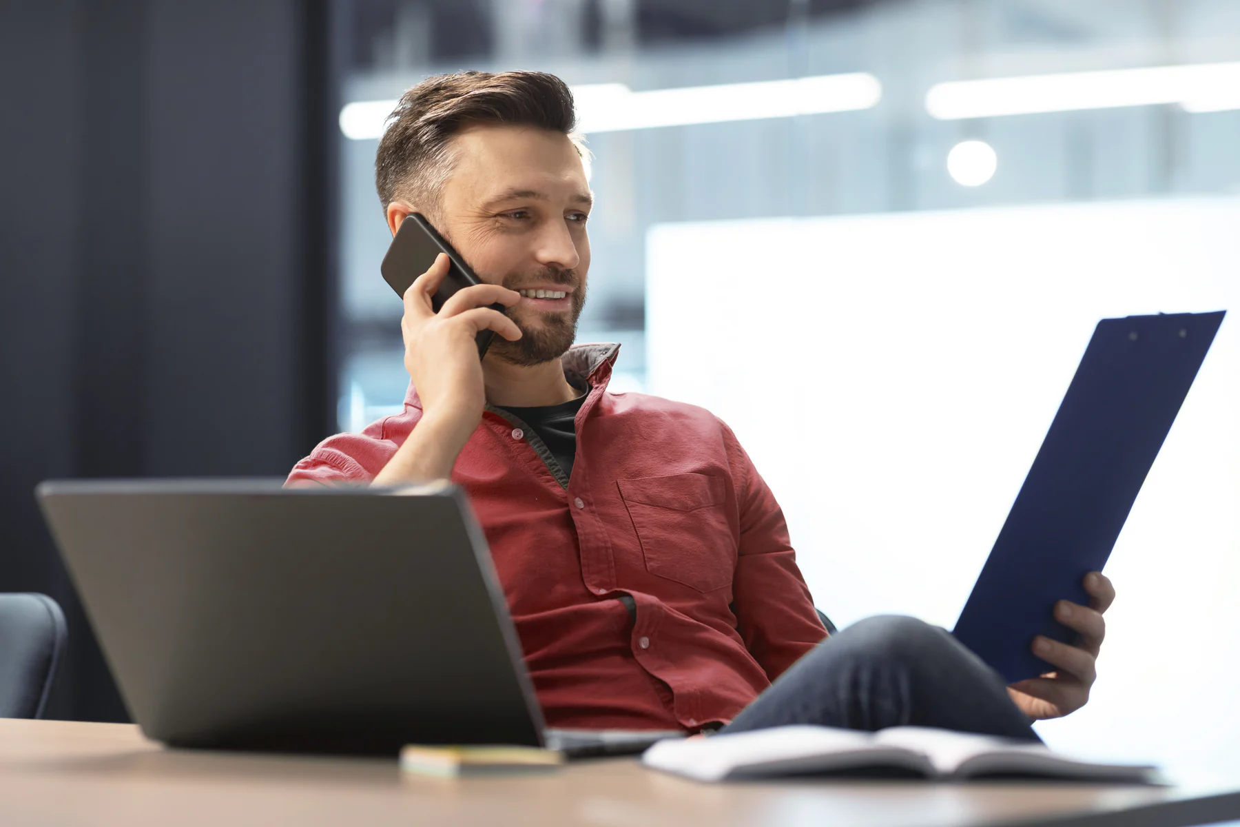 Business professional talking on the phone beside a laptop